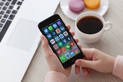 person holding a cell phone next to a computer