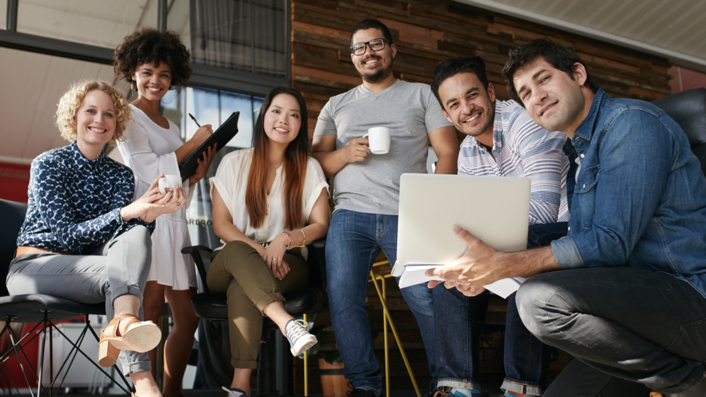 a group of diverse models holding coffee and laptops smiling