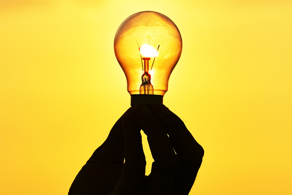 Stock image illustrating an idea whilst showing a lit lightbulb in and a black hand