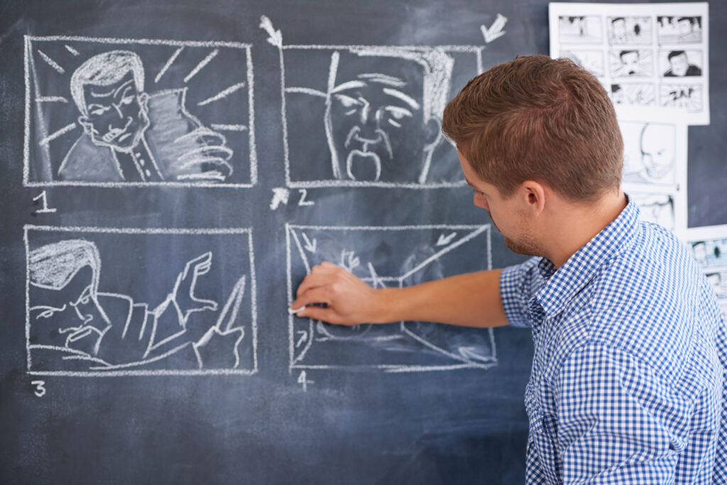 George's brother wearing a checkered shirt creating a storyboard on a chalk board